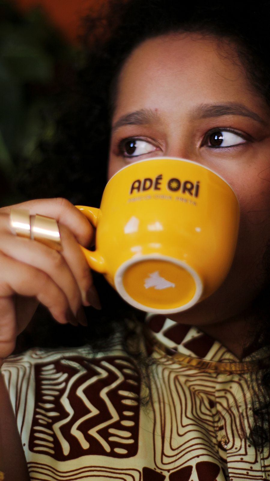 Marina Niambi bebendo em uma caneca amarela da Adé Orí
