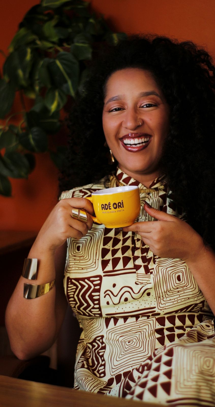 Marina Niambi sorrindo e segurando uma caneca amarela da Adé Orí