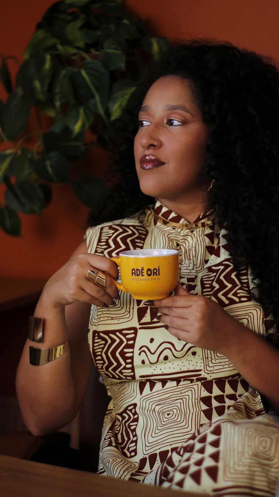 Marina Niambi segurando a caneca amarela da Adé Orí, com vestido de estampa ancestral